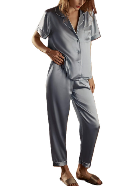 A woman wearing a gray silk pajama set with button front detail.