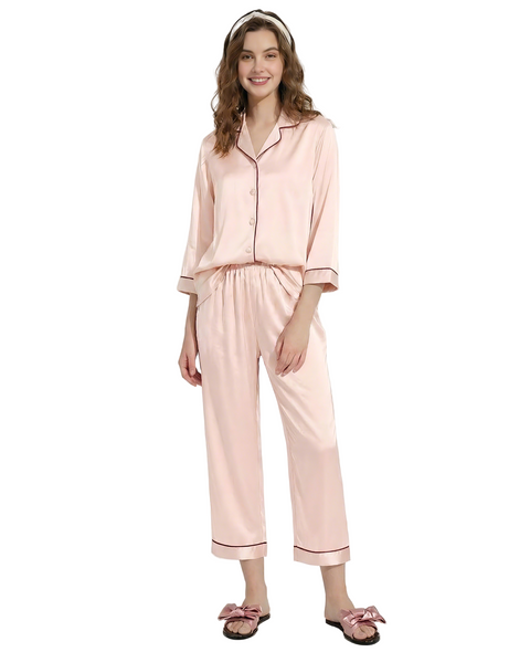 Woman wearing a pink satin pajama set on a white background