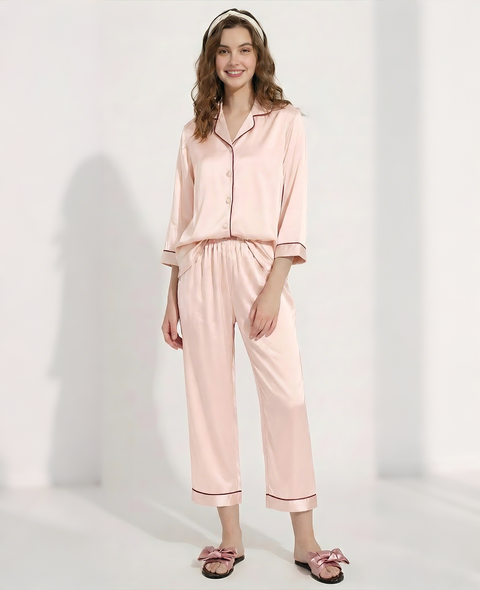 Woman wearing a pink satin pajama set on a white background