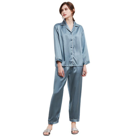 A woman wearing a gray silk pajama set with button front detail.